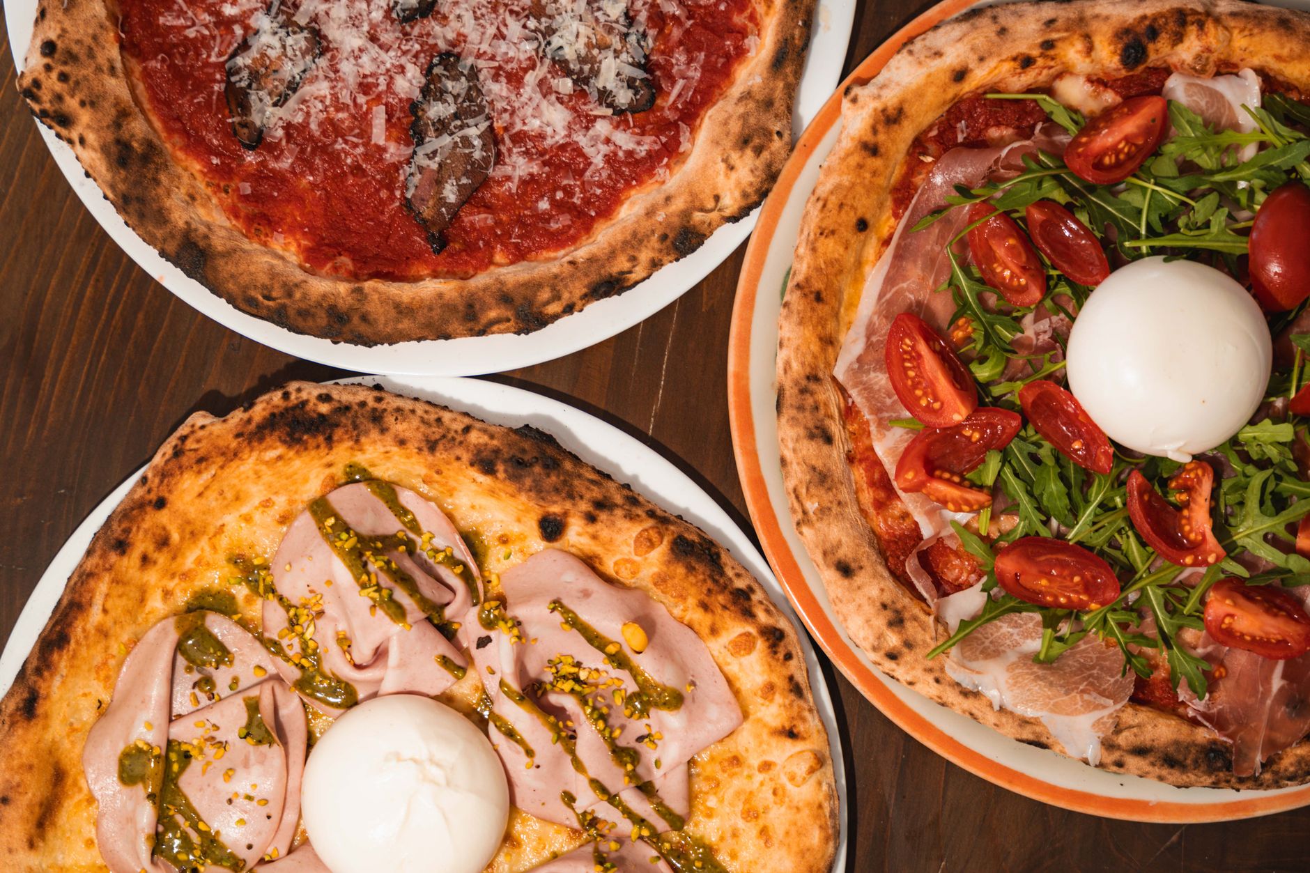 A close-up of various Italian pizzas with gourmet toppings, captured in an indoor Milan pizzeria.